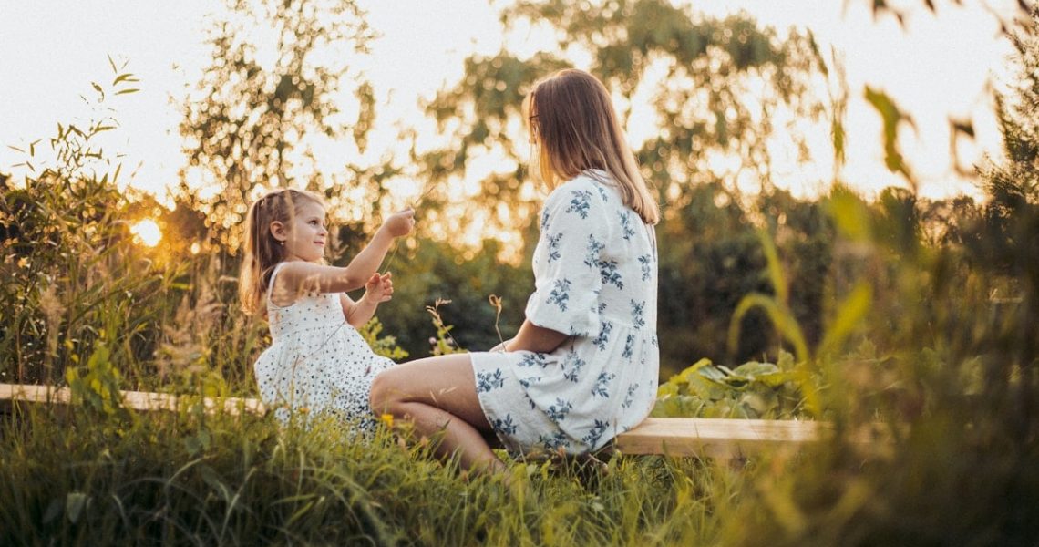a woman and a little girl sitting on a bench